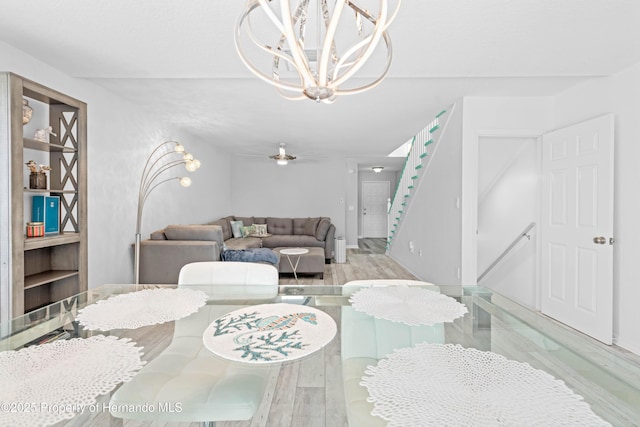dining area featuring an inviting chandelier, wood finished floors, and stairway