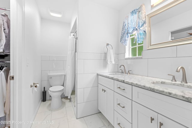 full bathroom featuring double vanity, a sink, toilet, and tile walls