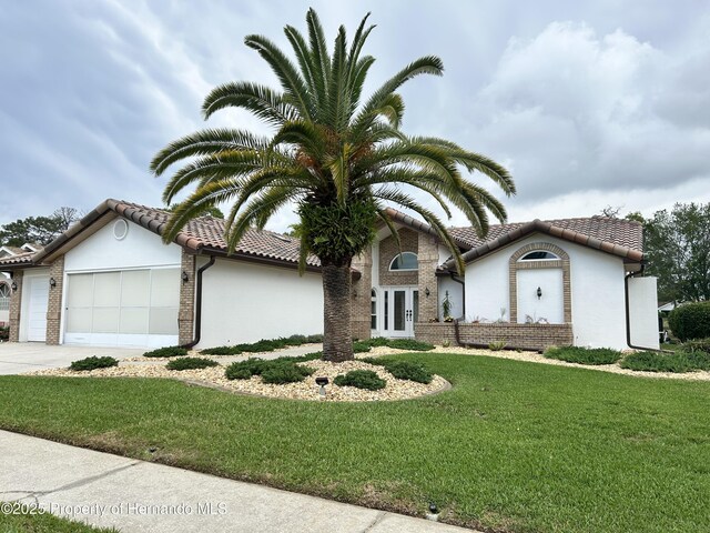 10519 Audie Brook Dr, Spring Hill, FL 34608 - view of front facade featuring an attached garage, a tiled roof, stucco siding, concrete driveway, and a front yard