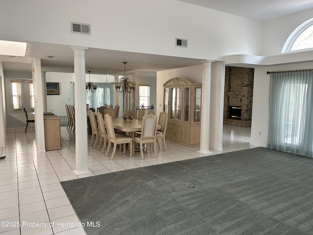 10519 Audie Brook Dr, Spring Hill, FL 34608 - dining room featuring ornate columns, light tile patterned floors, a high ceiling, a chandelier, and a fireplace