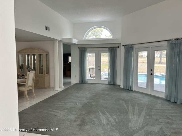 10519 Audie Brook Dr, Spring Hill, FL 34608 - entryway featuring french doors, a towering ceiling, carpet, decorative columns, and tile patterned flooring