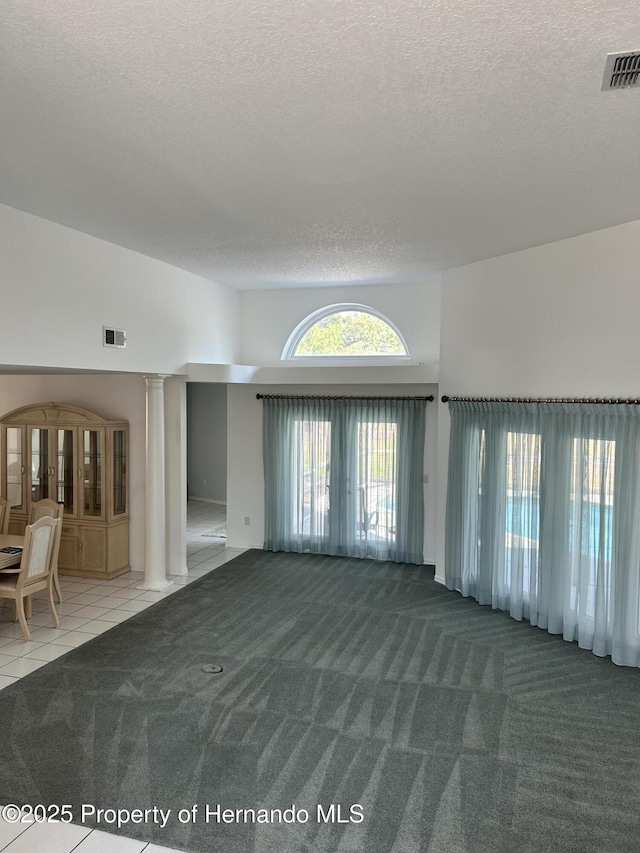 10519 Audie Brook Dr, Spring Hill, FL 34608 - carpeted empty room with a textured ceiling, decorative columns, and tile patterned flooring