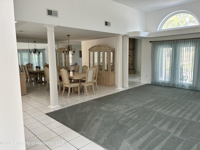 10519 Audie Brook Dr, Spring Hill, FL 34608 - dining room with decorative columns, light tile patterned floors, a high ceiling, a chandelier, and light colored carpet