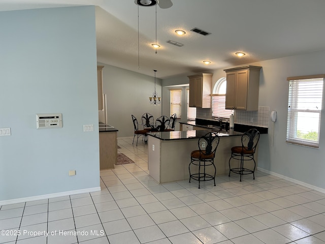 10519 Audie Brook Dr, Spring Hill, FL 34608 - kitchen with dark countertops, a peninsula, a breakfast bar area, decorative backsplash, and decorative light fixtures
