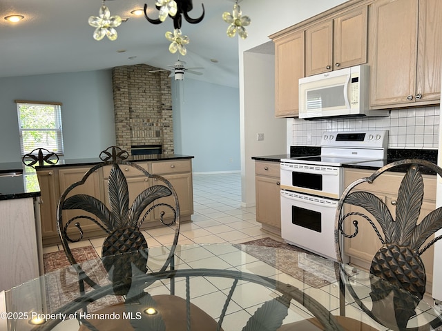 10519 Audie Brook Dr, Spring Hill, FL 34608 - kitchen with white appliances, lofted ceiling, dark countertops, light tile patterned flooring, and decorative backsplash