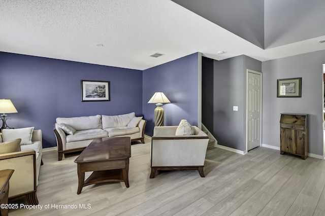 11257 Persimmon Ave, Weeki Wachee, FL 34614 - living room with a textured ceiling, visible vents, light wood finished floors, and baseboards