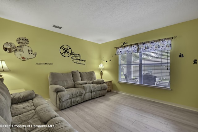 11257 Persimmon Ave, Weeki Wachee, FL 34614 - living room with a textured ceiling, visible vents, wood finished floors, and baseboards