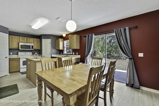 11257 Persimmon Ave, Weeki Wachee, FL 34614 - dining area with light wood finished floors, a textured ceiling, and visible vents