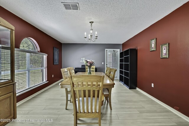 11257 Persimmon Ave, Weeki Wachee, FL 34614 - dining space featuring a textured ceiling, a chandelier, an accent wall, and visible vents