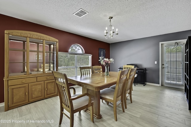 11257 Persimmon Ave, Weeki Wachee, FL 34614 - dining room with a textured ceiling, a notable chandelier, light wood-style floors, and plenty of natural light