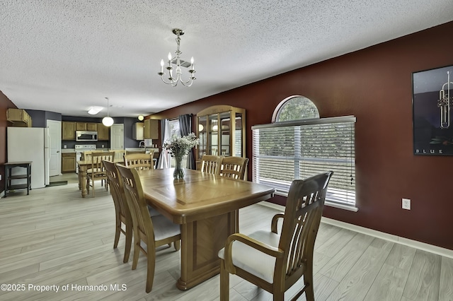 11257 Persimmon Ave, Weeki Wachee, FL 34614 - dining area with a textured ceiling, a chandelier, baseboards, and light wood-style floors