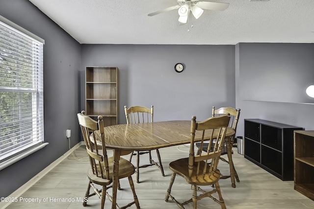 11257 Persimmon Ave, Weeki Wachee, FL 34614 - dining room featuring a textured ceiling, ceiling fan, light wood-style floors, and baseboards