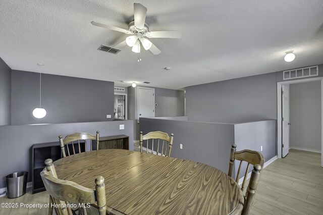 11257 Persimmon Ave, Weeki Wachee, FL 34614 - dining room featuring light wood-type flooring, visible vents, a ceiling fan, and a textured ceiling