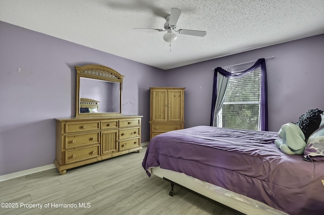 11257 Persimmon Ave, Weeki Wachee, FL 34614 - bedroom with a textured ceiling, a ceiling fan, light wood finished floors, and baseboards