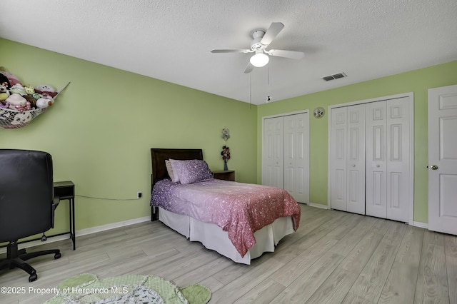 11257 Persimmon Ave, Weeki Wachee, FL 34614 - bedroom featuring a textured ceiling, visible vents, wood finished floors, and two closets