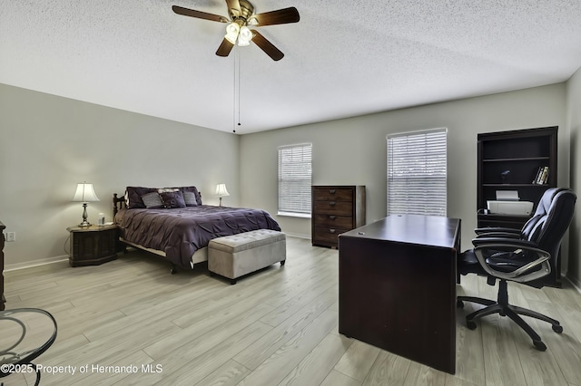 11257 Persimmon Ave, Weeki Wachee, FL 34614 - bedroom featuring a textured ceiling, a ceiling fan, baseboards, and light wood-style floors