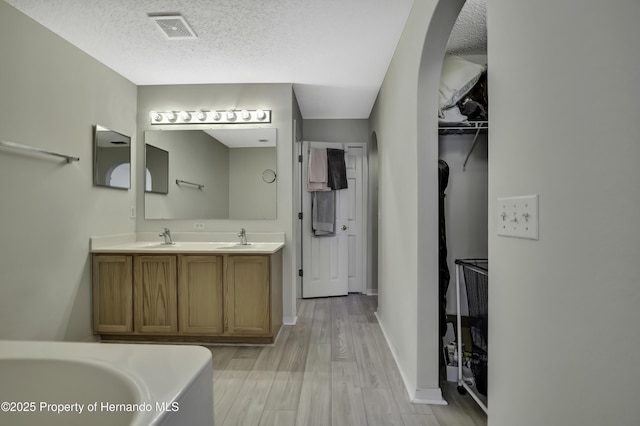 11257 Persimmon Ave, Weeki Wachee, FL 34614 - full bathroom featuring a sink, a textured ceiling, visible vents, and wood finished floors