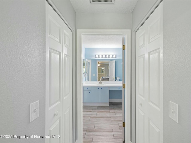 18441 Whitacre Cir, Hudson, FL 34667 - hall featuring visible vents, wood tiled floor, a textured wall, and a sink