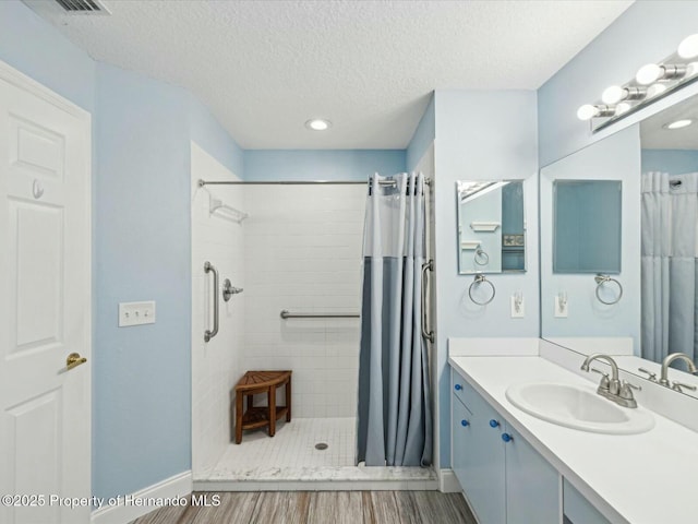 18441 Whitacre Cir, Hudson, FL 34667 - full bathroom featuring a textured ceiling, baseboards, wood finished floors, vanity, and tiled shower