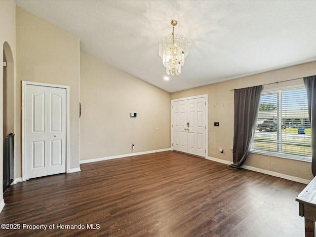 interior space with a notable chandelier, vaulted ceiling, baseboards, arched walkways, and wood finished floors