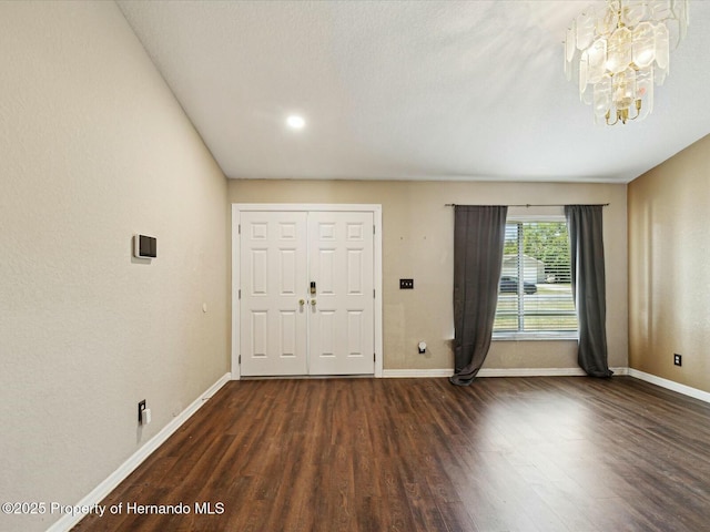 entrance foyer with baseboards, wood finished floors, and a notable chandelier