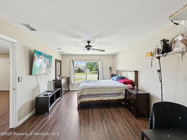 bedroom with dark wood-style floors, a textured ceiling, visible vents, and ceiling fan