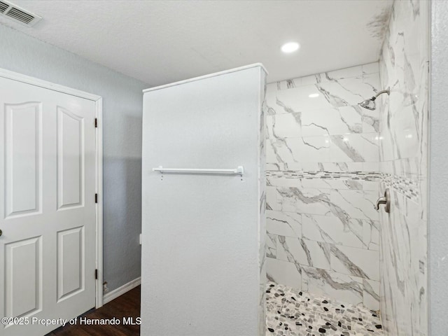 full bathroom with a tile shower, recessed lighting, visible vents, and baseboards