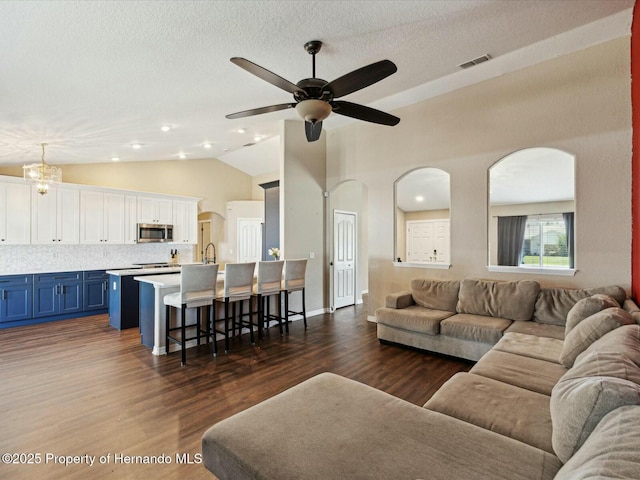 living area with dark wood-style flooring, visible vents, ceiling fan, and arched walkways