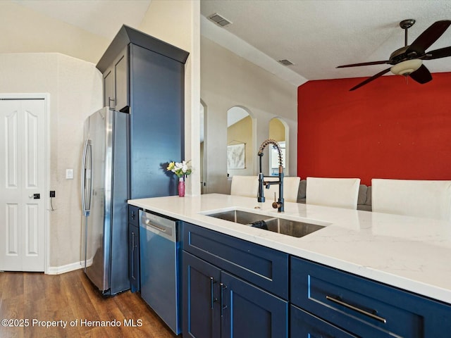 kitchen featuring lofted ceiling, a sink, visible vents, stainless steel appliances, and blue cabinets