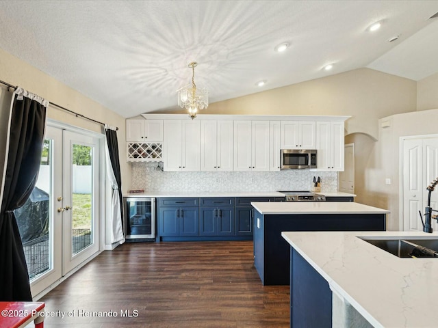 kitchen with stainless steel microwave, wine cooler, a sink, and lofted ceiling