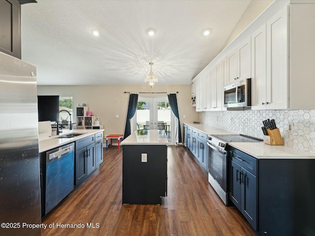 kitchen featuring a sink, appliances with stainless steel finishes, light countertops, a center island, and dark wood-style flooring