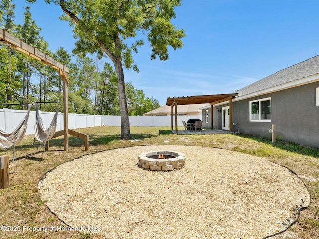 view of yard with a fire pit, fence, and a patio area