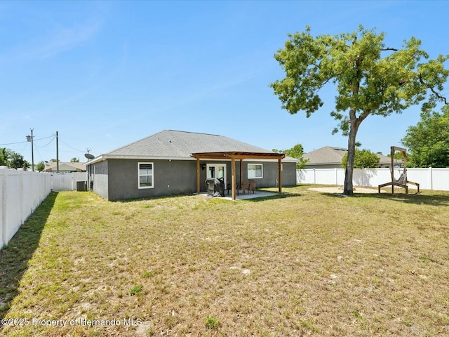 rear view of property featuring stucco siding, a yard, a patio area, and a fenced backyard