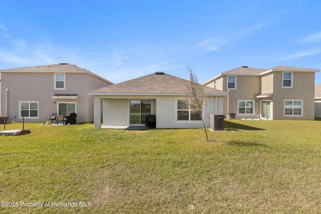 rear view of property with a shingled roof, cooling unit, a yard, and stucco siding