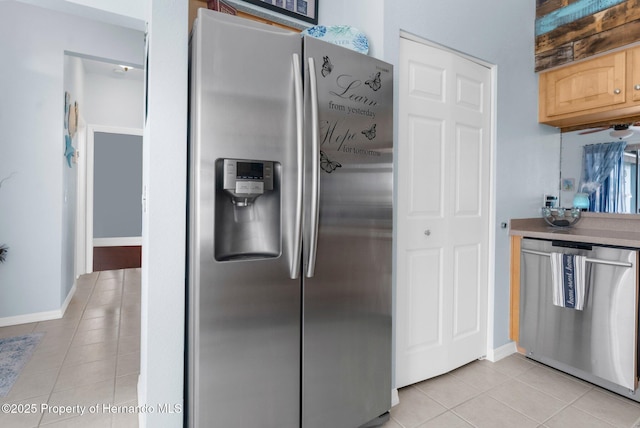 kitchen with baseboards, light tile patterned flooring, and stainless steel appliances