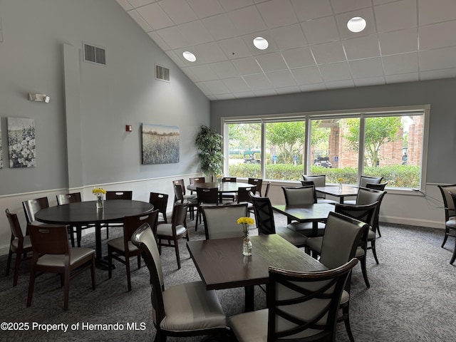 dining area with high vaulted ceiling, a wealth of natural light, carpet, and visible vents