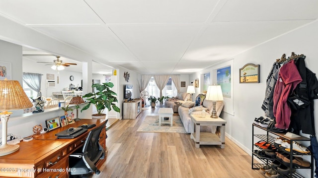 living area with light wood-style floors, baseboards, and a ceiling fan