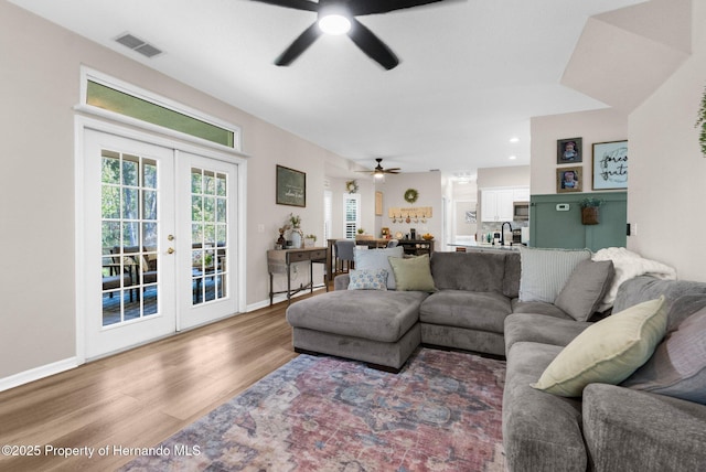 living area with french doors, a ceiling fan, visible vents, wood finished floors, and baseboards