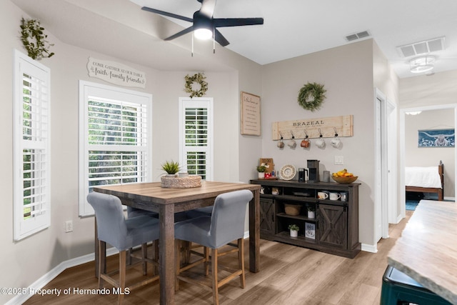 dining space with light wood-style floors, baseboards, ceiling fan, and visible vents