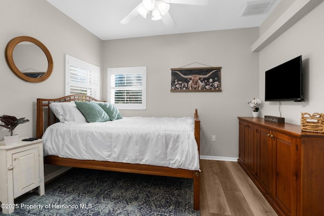bedroom with visible vents, a ceiling fan, baseboards, and wood finished floors