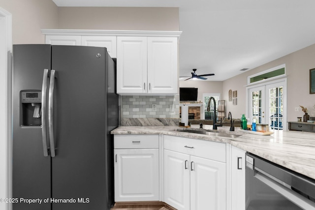 kitchen with ceiling fan, backsplash, a sink, stainless steel appliances, and white cabinetry