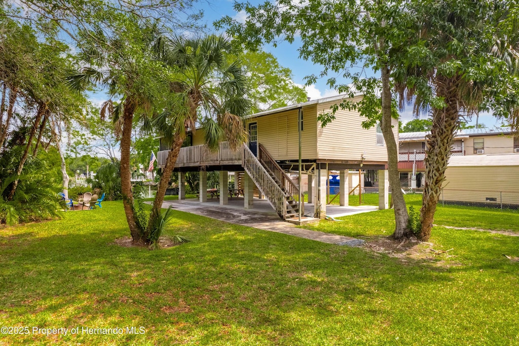 rear view of property with stairway, a lawn, and a carport