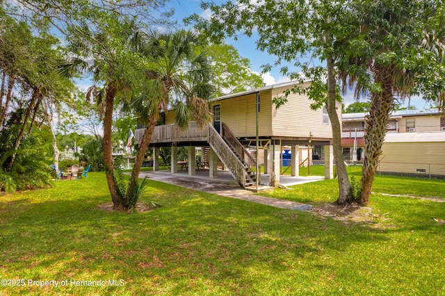 rear view of property with stairway, a lawn, and a carport