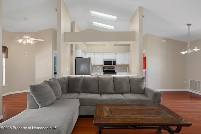 living room featuring visible vents, ceiling fan with notable chandelier, dark wood-style floors, and a skylight