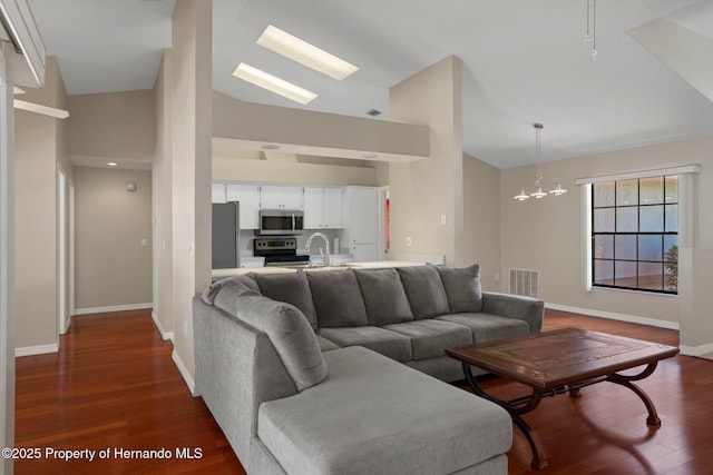 living room featuring a notable chandelier, high vaulted ceiling, baseboards, dark wood-type flooring, and visible vents