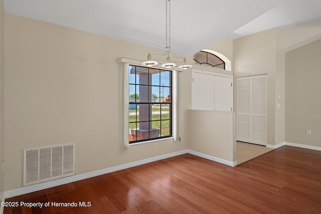 unfurnished dining area with baseboards, a chandelier, wood finished floors, and visible vents