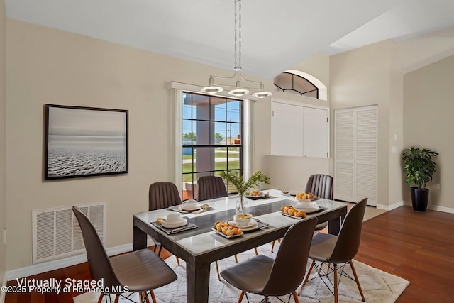 dining space with a chandelier, baseboards, visible vents, and wood finished floors