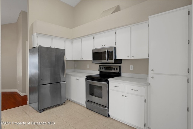 kitchen with light countertops, appliances with stainless steel finishes, white cabinets, and baseboards