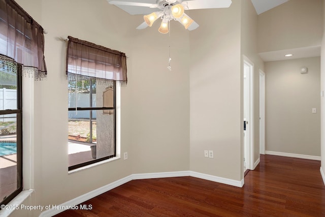 unfurnished dining area with baseboards, a ceiling fan, a high ceiling, and wood finished floors