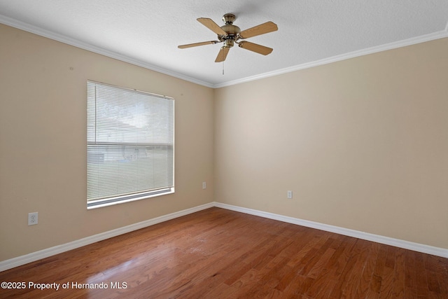 unfurnished room with baseboards, a ceiling fan, crown molding, and wood finished floors